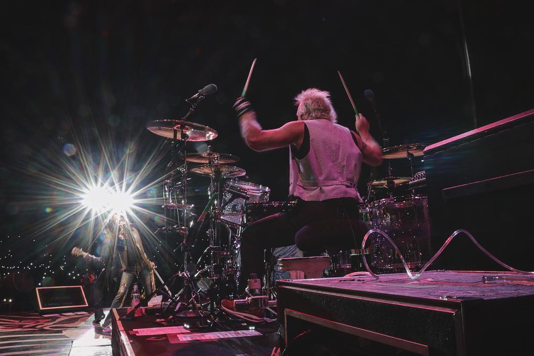 a drummer playing on a concert stage among millions of fans