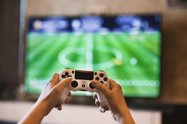 playing soccer or football using playstation while sitting on a couch