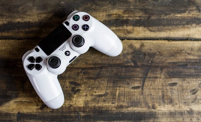 a white video game controller for playstation on a wooden platform