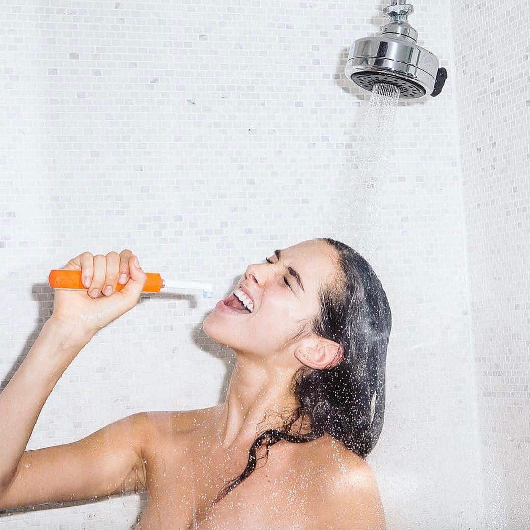 a girl singing in the shower while brushing her teeth