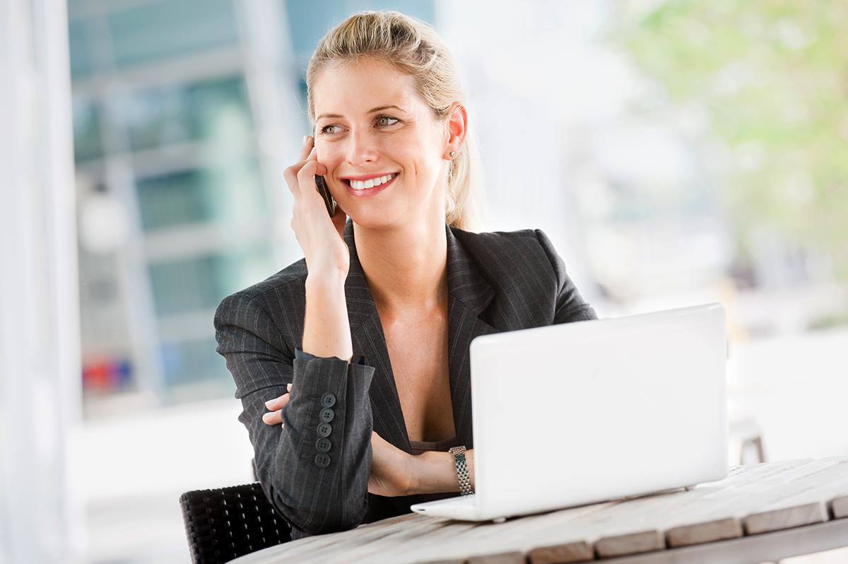 a woman talking on the phone while sitting in front of her laptop