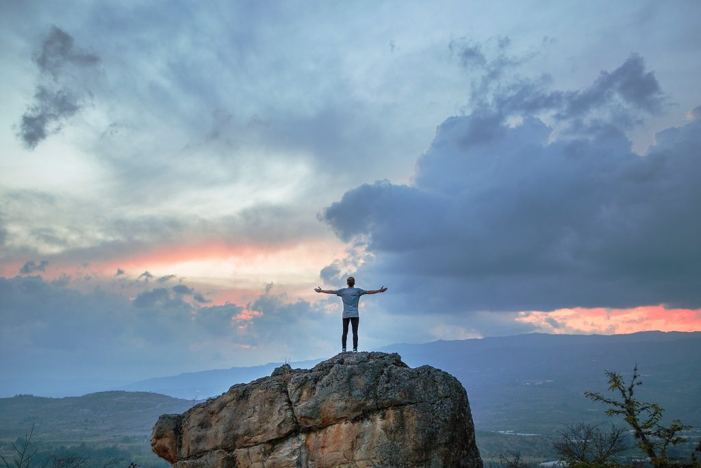 man spreading his arms while on top of a mountain 