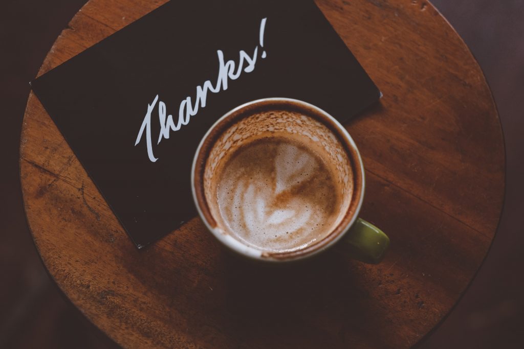a cup of coffee with a thank you card