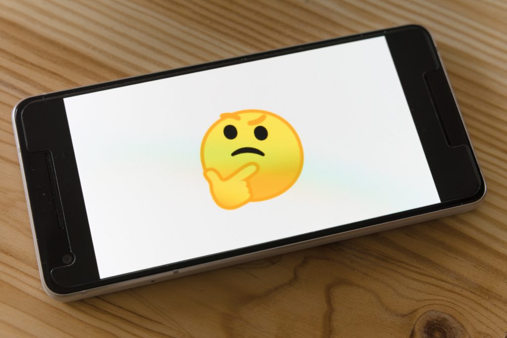 a phone with an emoji of someone thinking