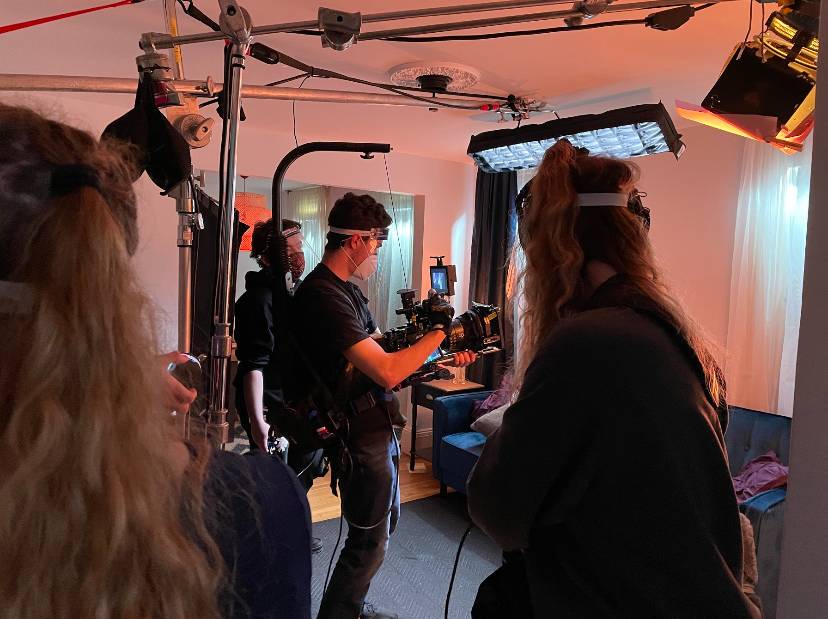 A team of individuals in a room, interacting with a camera, highlighting a moment of creativity and collaboration.