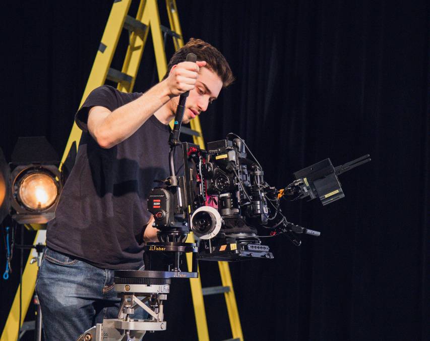 On stage, a man with a camera captures the essence of creativity at The Farm SoHo event featuring Eitan Miller.