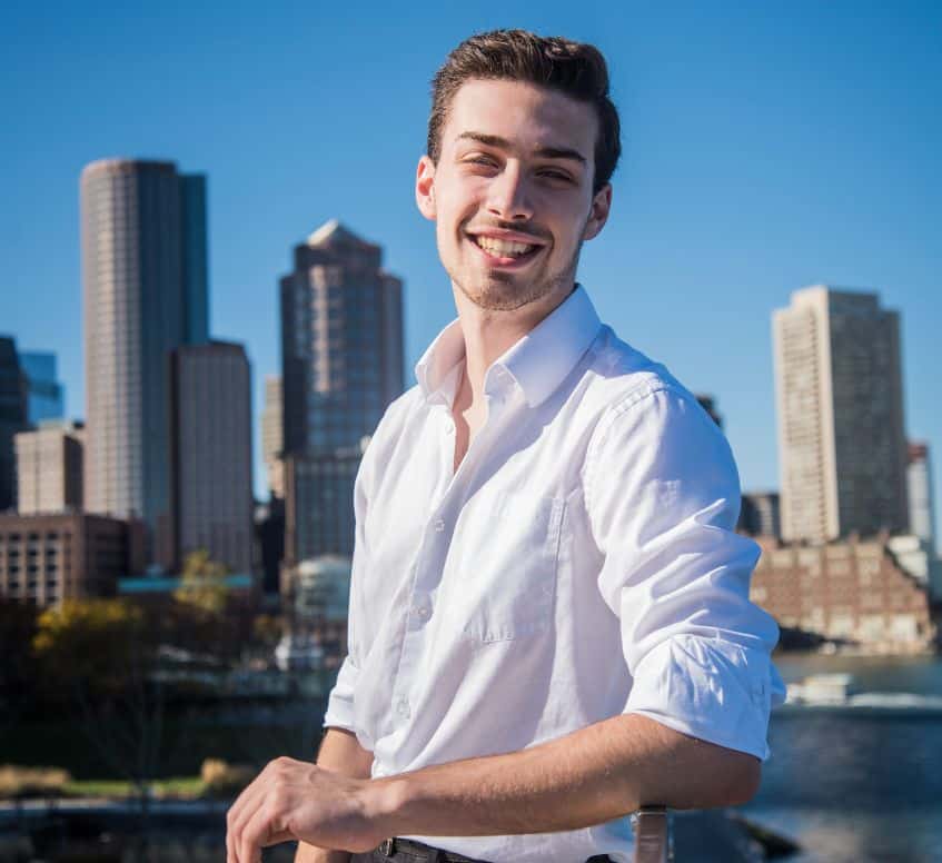 A young man in a white shirt stands confidently on a bridge, embodying professionalism and creativity.