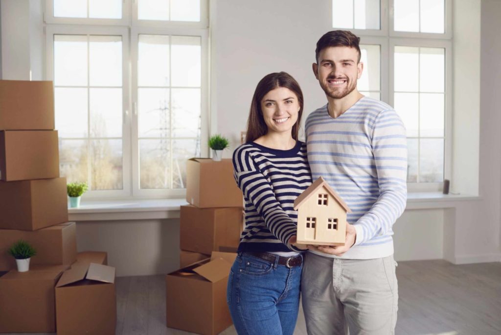 a married couple holding a wooden house
