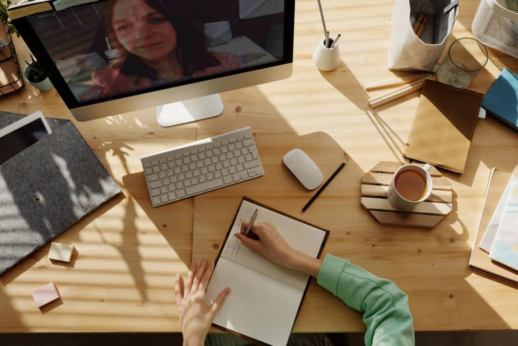 woman taking notes while on a video call