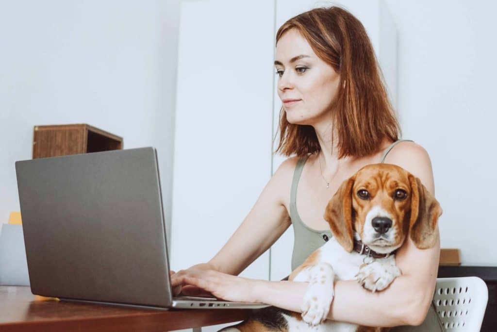 woman holding her dog while working from home
