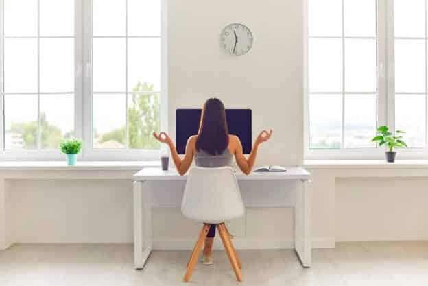 a woman at her workstation giving hand gestures indicating happiness thanks to employee engagement

