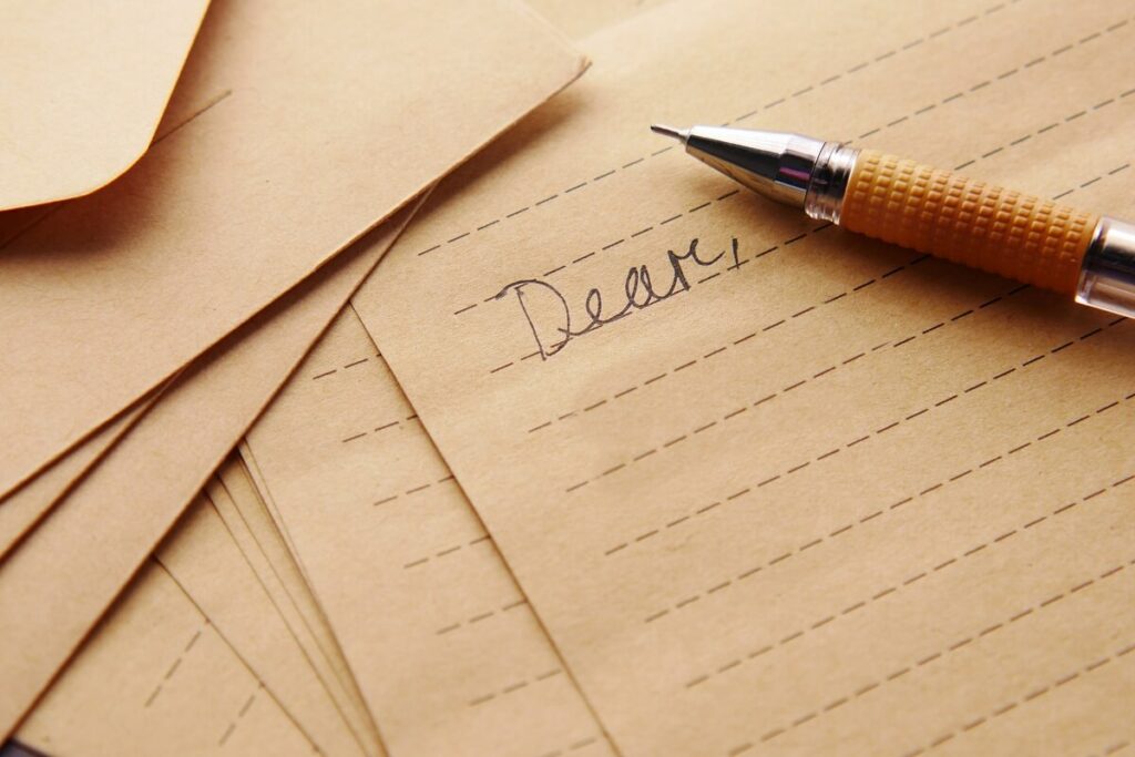 photograph of a pen laid on sheets of writing paper with the opening line of a letter of resignation