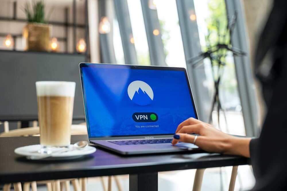 photograph of a remote worker in front of a laptop displaying VPN on the screen