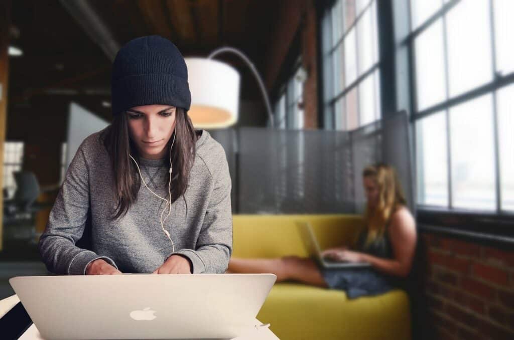 photograph of two young women focused on their laptops in a coworking space