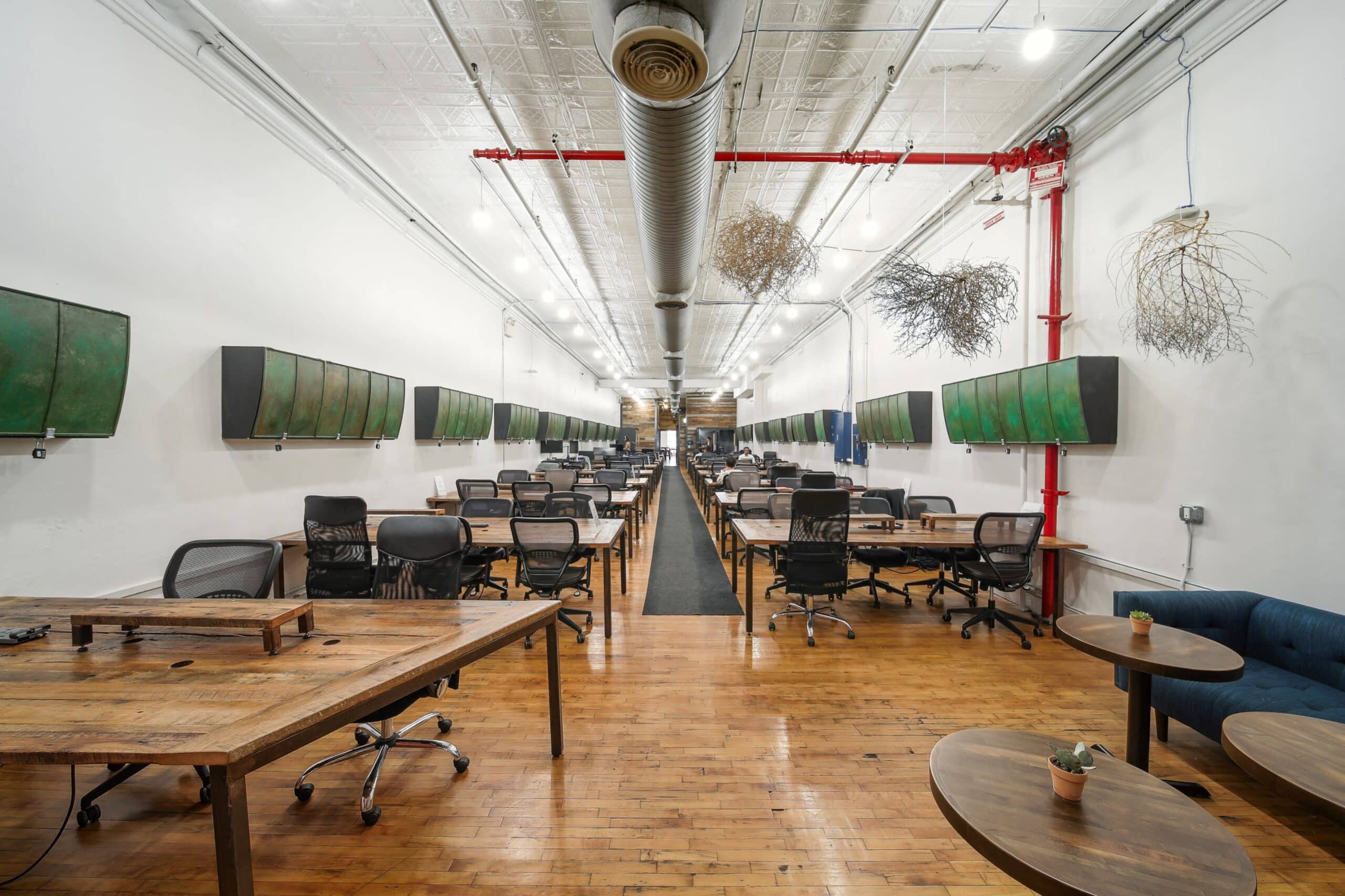 An elegant office interior showcasing wooden flooring and tables, ideal for a focused work environment.