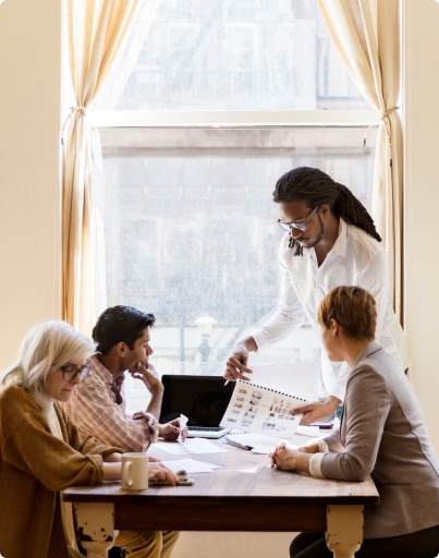 A woman is positioned at a table with three colleagues, participating in a collaborative meeting in an office environment.