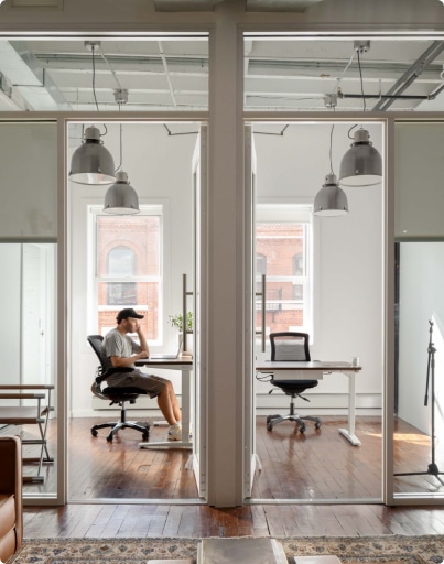 A man seated at a desk in a modern open office environment, focused on his work amidst a collaborative space.